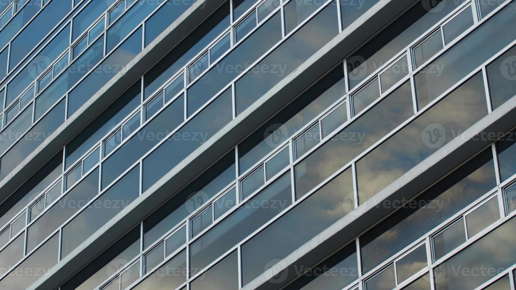 Annäherung an die Glasfenster, die einen blauen Himmel eines modernen Gebäudes reflektieren. abstrakter Hintergrund foto