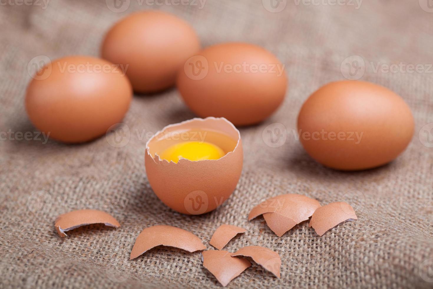 frische Eier auf Sackleinen, zerbrochene Eierschale, Eigelb foto