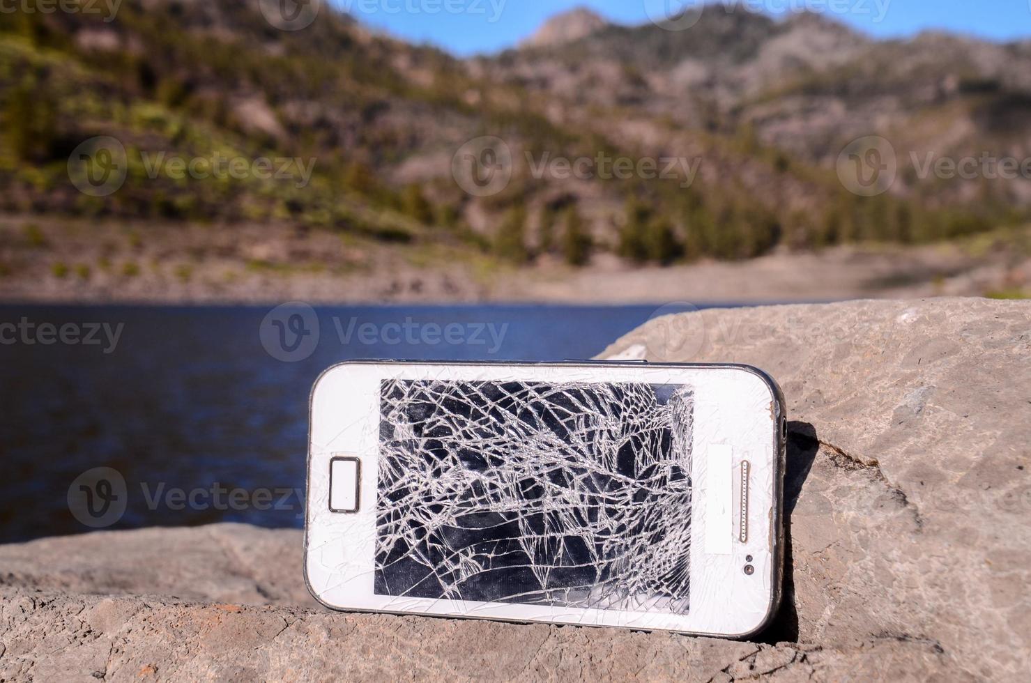 kaputtes Telefon auf einem Felsen foto