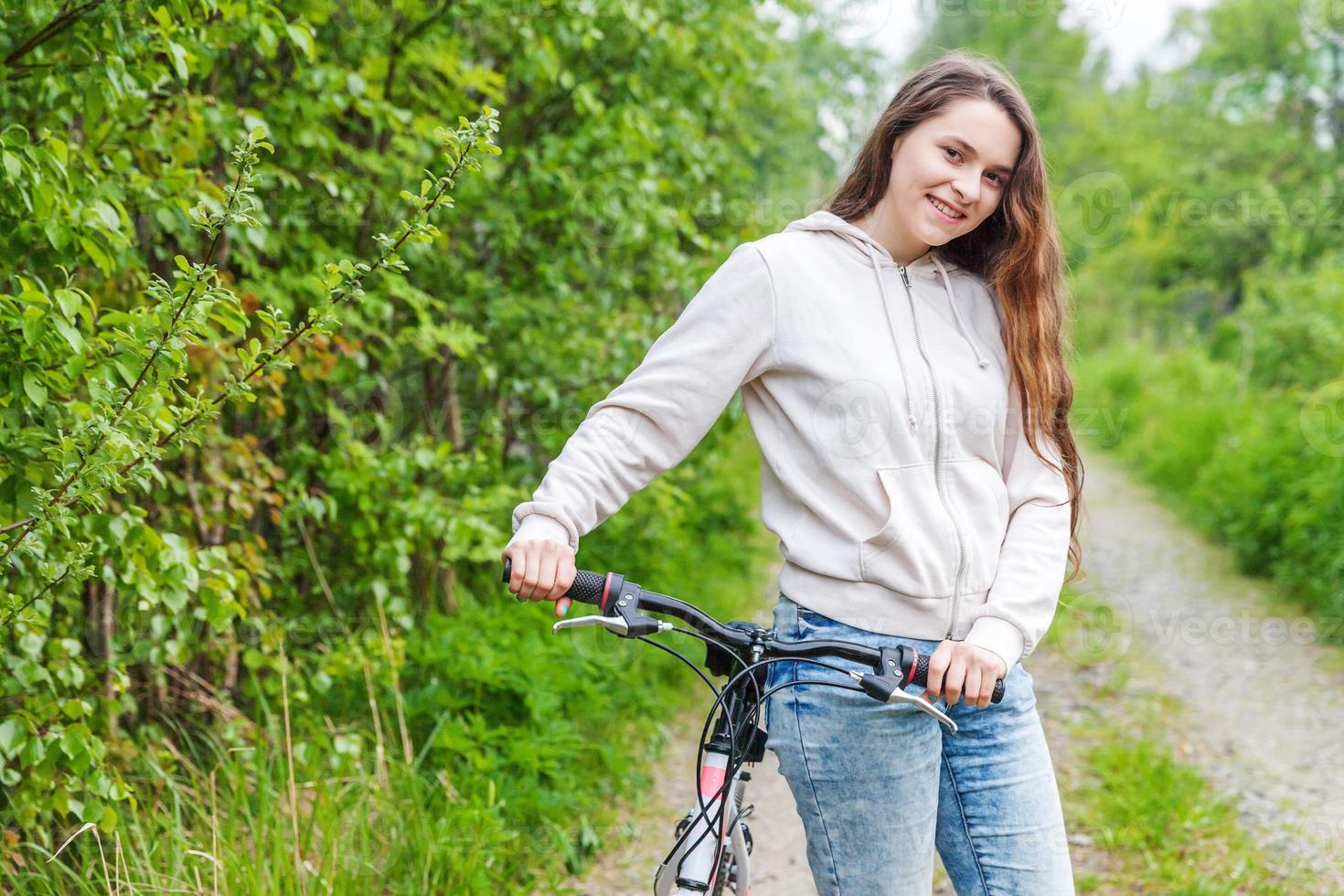 junge frau, die fahrrad im sommerstadtpark draußen fährt. aktive Menschen. Hipster-Mädchen entspannen und Fahrrad fahren foto