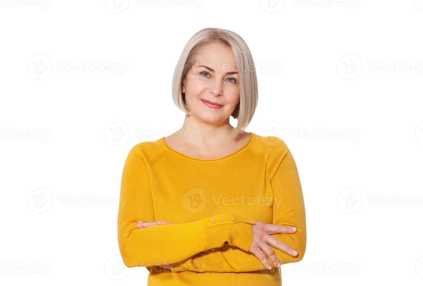 Blondine mittleren Alters posiert emotional in einem Studio. glückliche Frau im gelben hellen Pullover auf weißem Hintergrund foto