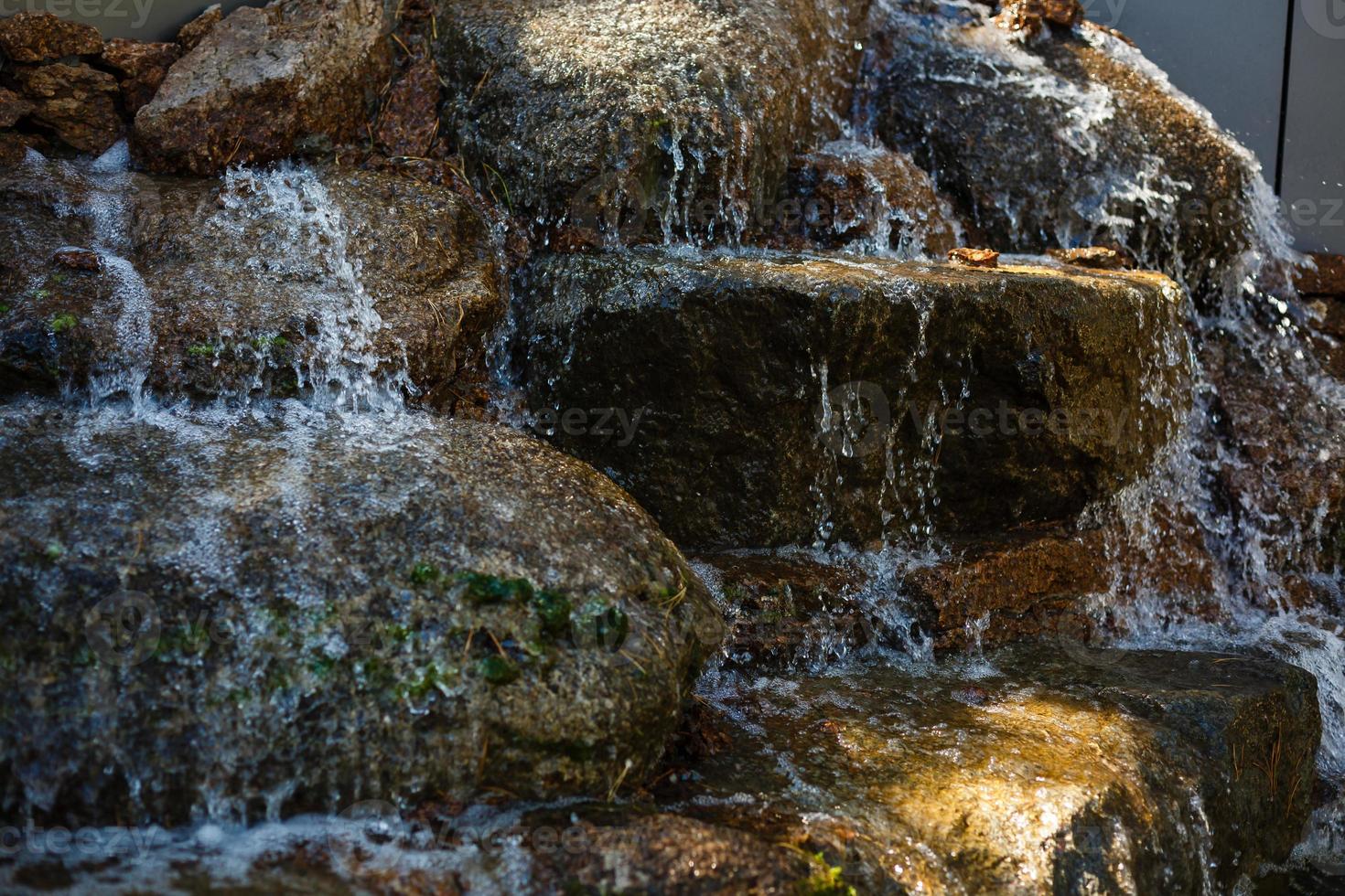 Nahaufnahme von Wasser, das von einem Wasserfall auf Felsen spritzt foto