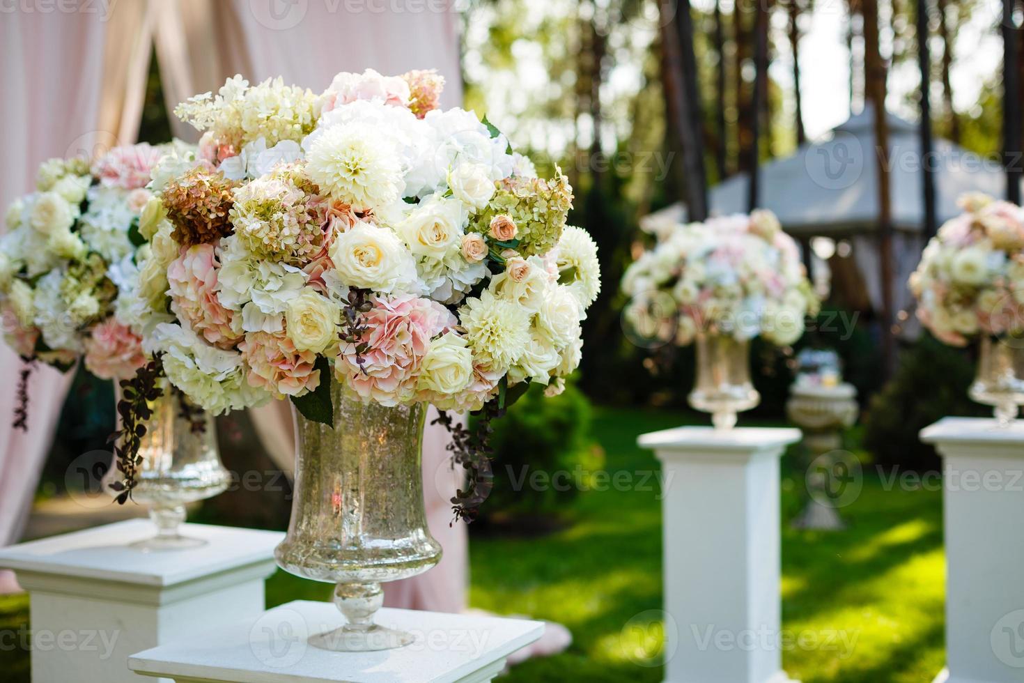 Hohe Kristallvase mit wunderschönem Blumenstrauß aus Gänseblümchen und Rosen darauf foto