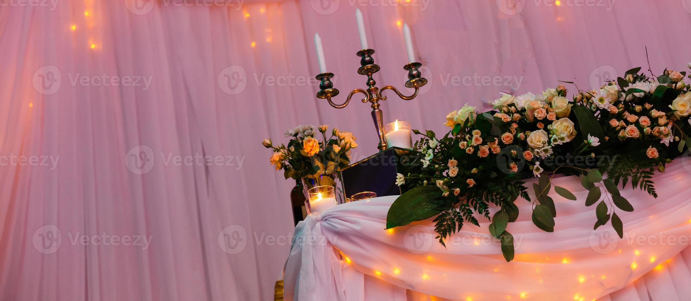 Hochzeit im Stil rustikal. Tischdekoration mit Lampen und Leuchter. der elegante Esstisch. Hochzeitsempfang im Innenbereich mit festlichem Dekor. Tische für das Brautpaar mit Blumen foto