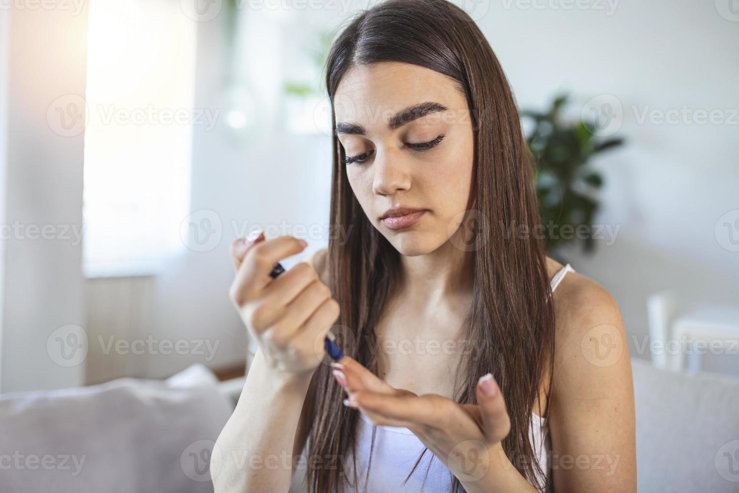 Frau mit Lanzette am Finger. Frau macht Blutzuckertest zu Hause in einem Wohnzimmer. Diabeteskontrolle foto