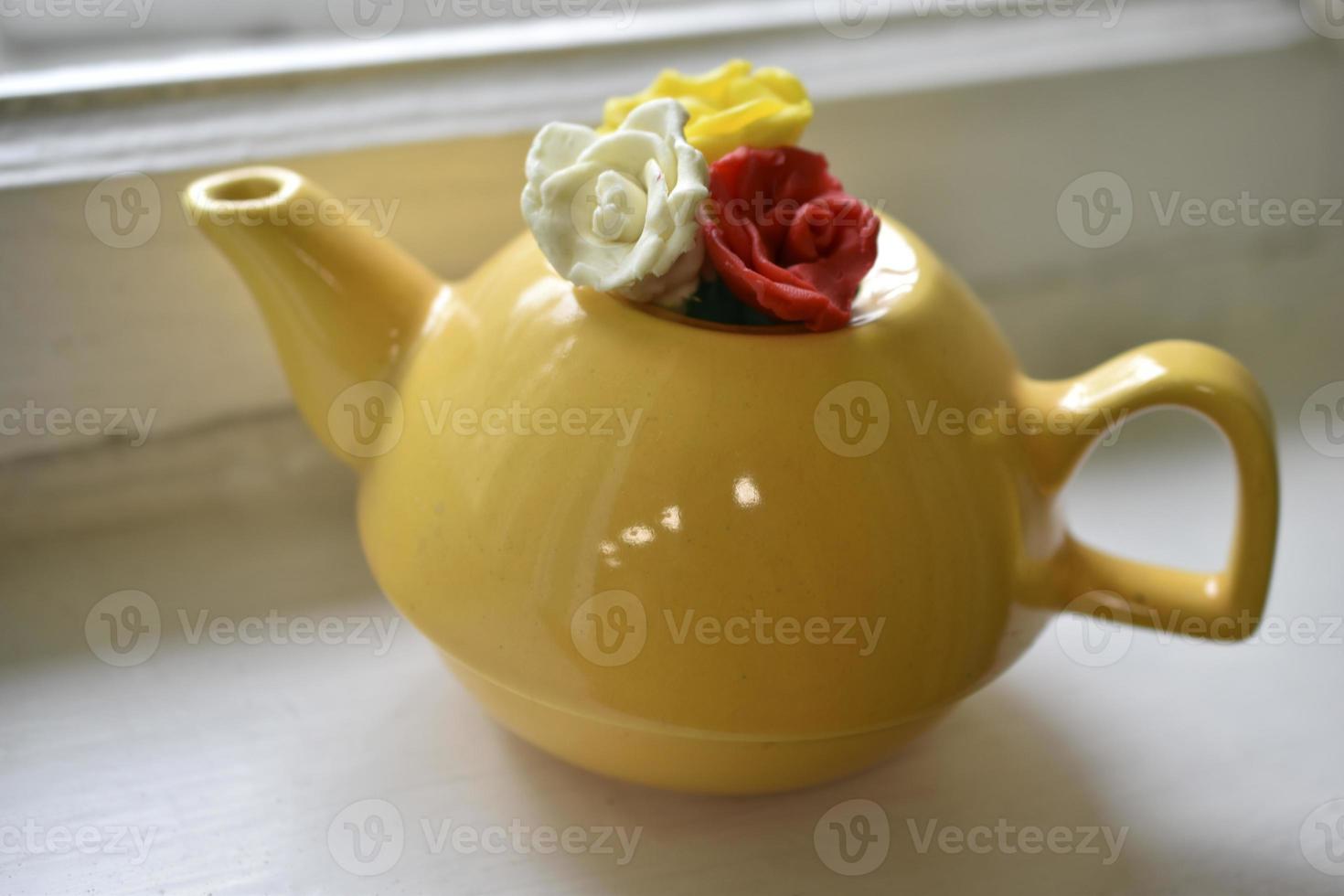 gelbe dekorative Teekanne auf der Fensterbank. Teekanne mit dekorativen Blumen. foto