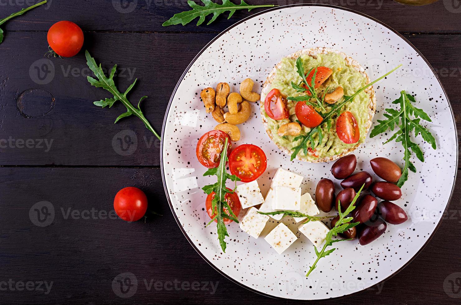 gesunde Avocado-Toasts zum Frühstück oder Mittagessen, Guacamole-Avocado, Kalamata-Oliven, Tomaten, Cashewnüsse und Feta-Käse. vegetarische Sandwiches. Ansicht von oben foto