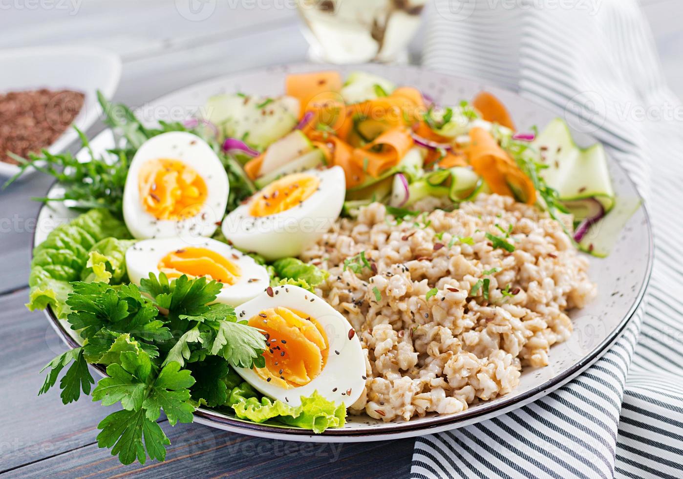 Frühstücksschüssel mit Haferflocken, Zucchini, Salat, Karotten und gekochtem Ei. frischer Salat. gesundes Essen. Vegetarische Buddha Bowl. foto