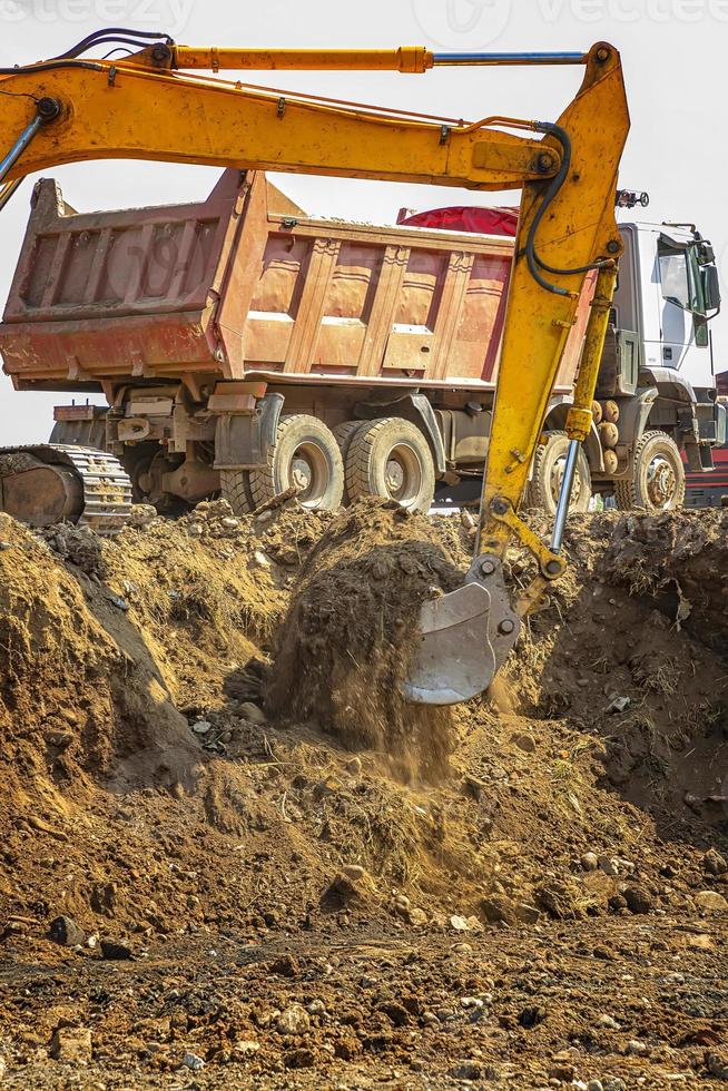 Gelber Bagger und leerer Muldenkipper, der auf der Baustelle arbeitet. vertikale Ansicht foto