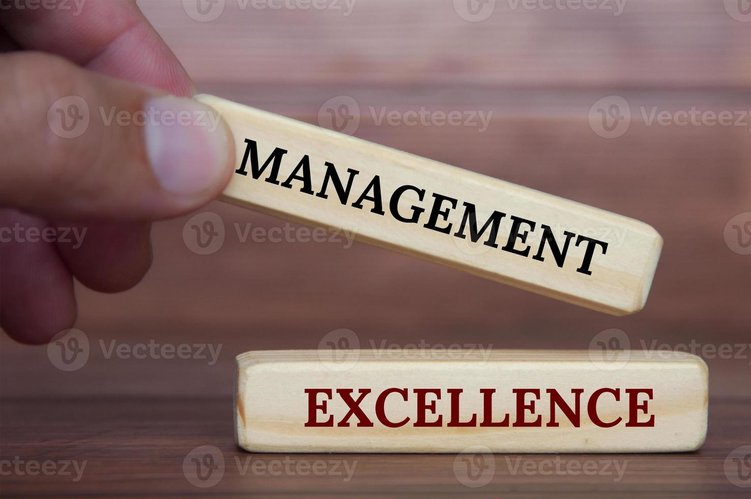 Hand, die Management-Excellence-Text auf Holzklötzen hält. Management-Exzellenz und Geschäftskonzept foto