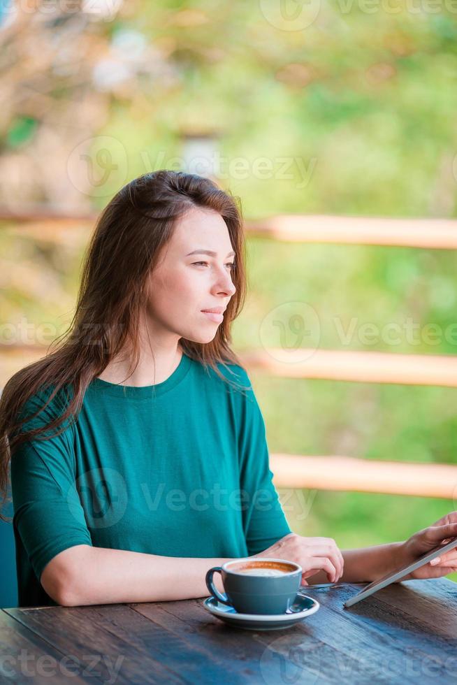 junge Frau mit Smartphone, während sie in der Freizeit allein im Café sitzt foto