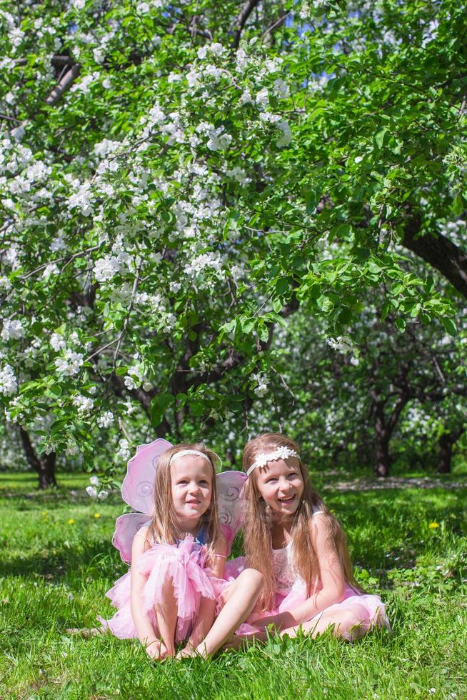 kleine Mädchen mit Schmetterlingsflügeln im blühenden Apfelgarten foto