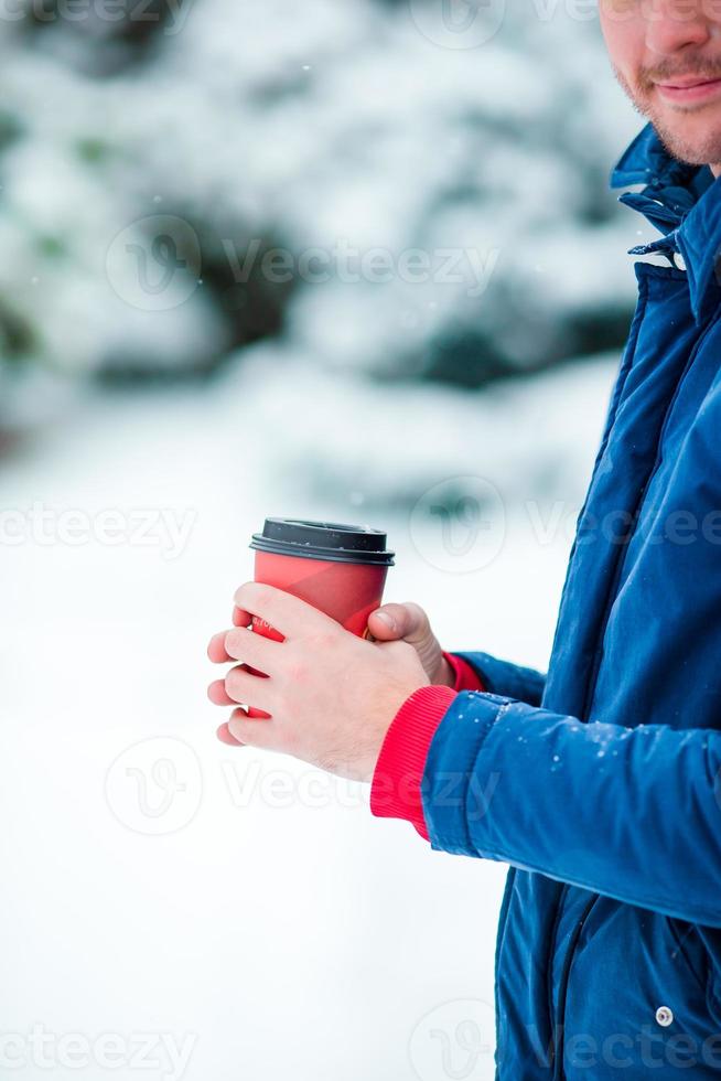 Nahaufnahmekaffee zum Mitnehmen in männliche Hände an gefrorenen Wintertagen im Freien foto