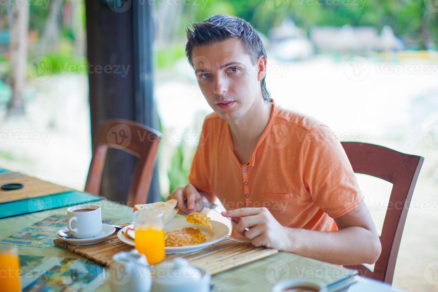 junger Mann beim Frühstück im Restaurant des Resorts foto