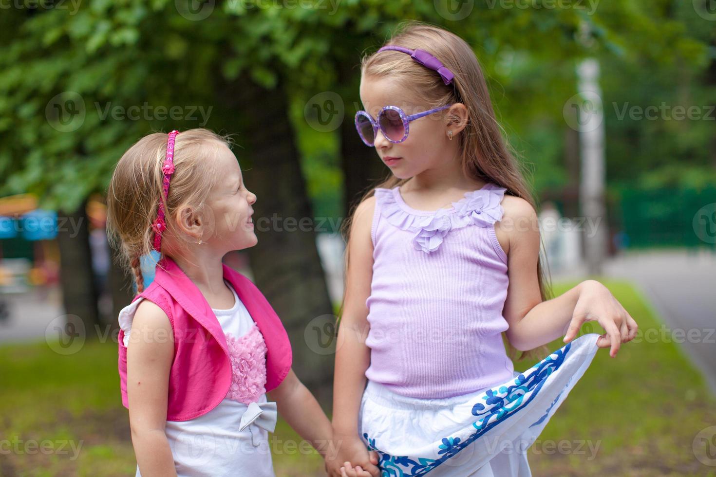 Zwei süße Modeschwestern gehen im Park Hand in Hand foto