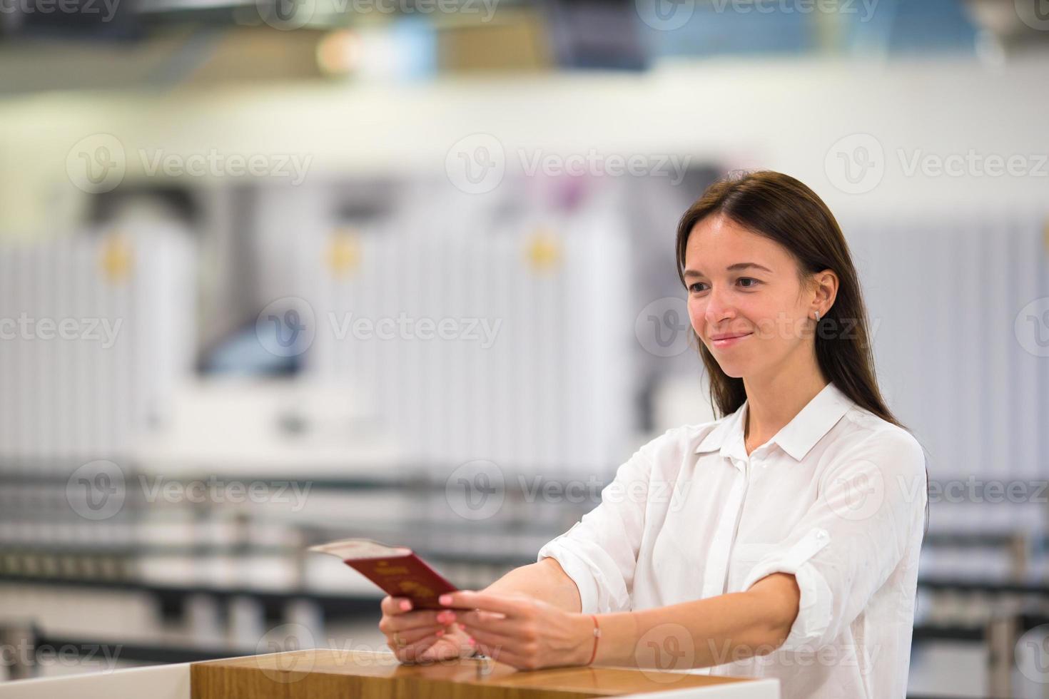 Schöne Frau mit Pässen und Bordkarten an der Rezeption am Flughafen foto