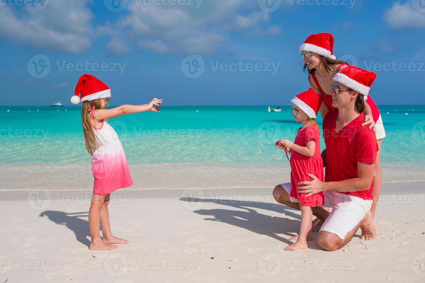 familie in weihnachtsmützen, die spaß am tropischen strand haben foto