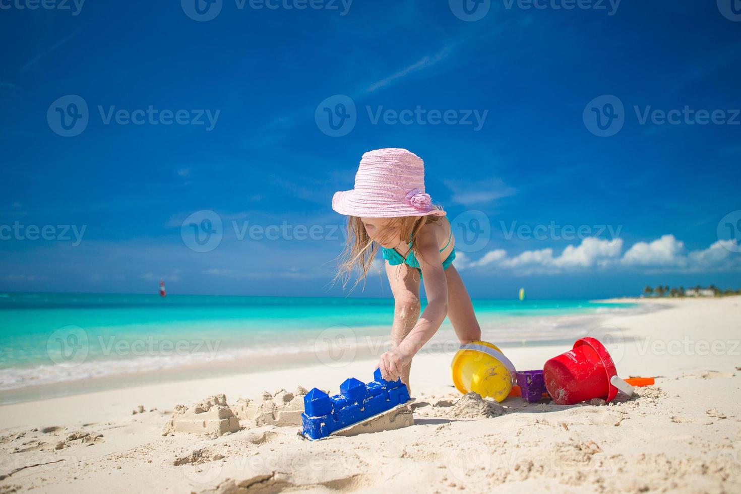 kleines Mädchen, das mit Strandspielzeug während des tropischen Urlaubs spielt foto