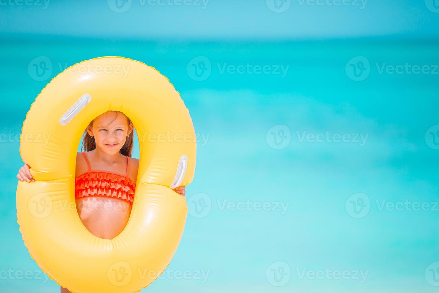 glückliches kind mit aufblasbarem gummikreis, der spaß am strand hat foto