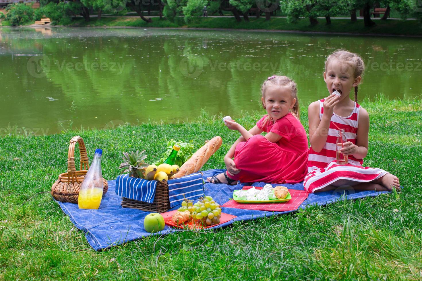 süße kleine Mädchen, die an sonnigen Tagen im Park picknicken foto