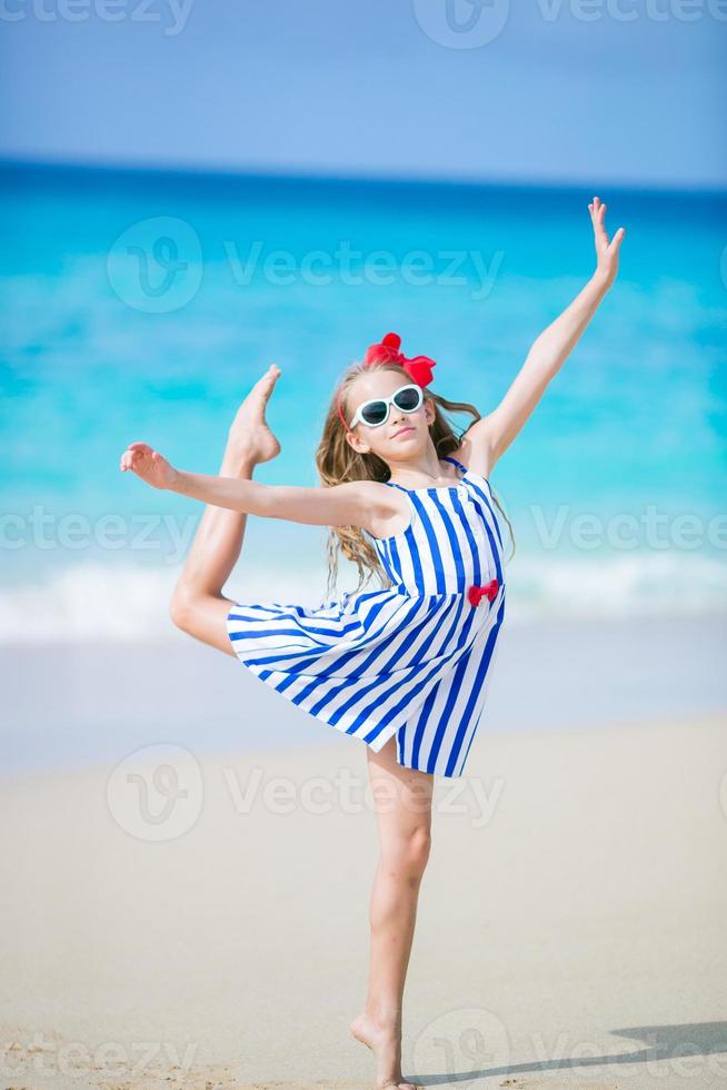 aktives kleines mädchen am strand, das viel spaß hat. sportliches Kind, das die Sportartikel an der Küste herstellt foto