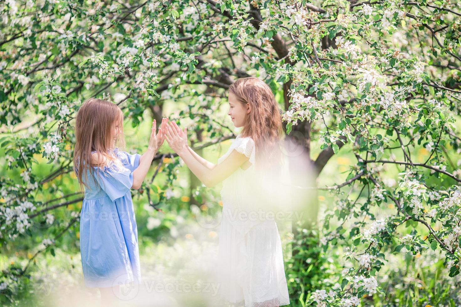 Entzückende kleine Mädchen im blühenden Apfelbaumgarten am Frühlingstag foto