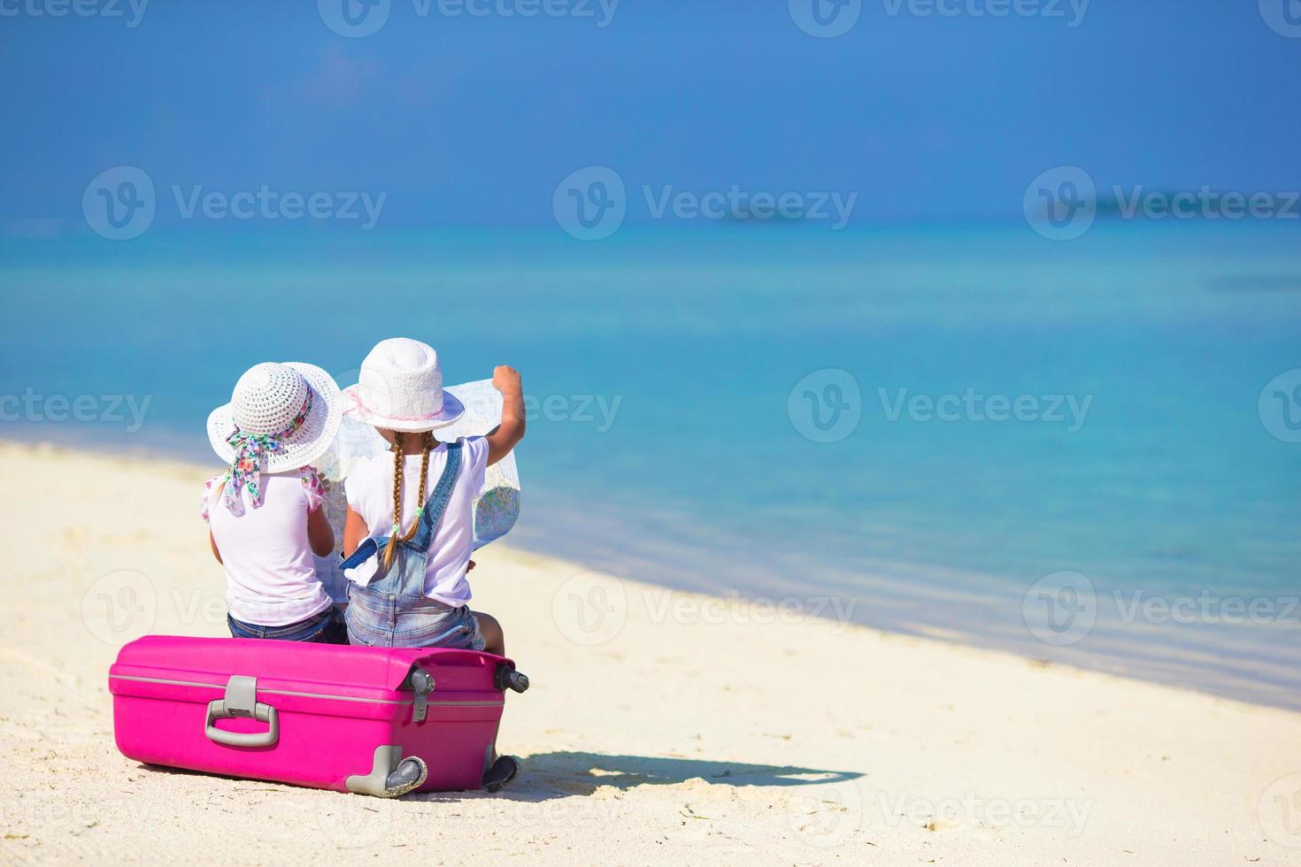 kleine Mädchen mit großem Koffer und Karte am tropischen Strand foto