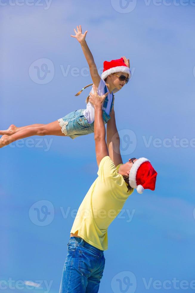 kleines mädchen und glücklicher vater in weihnachtsmütze während des strandurlaubs foto