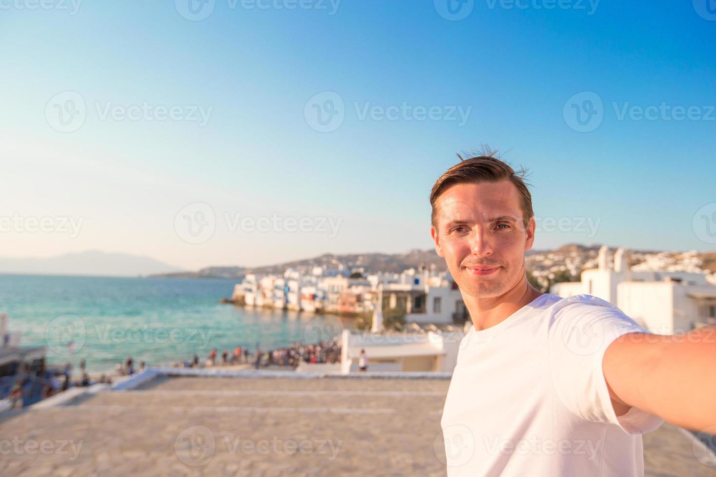 junger mann, der selfie porträthintergrund klein-venedig in mykonos nimmt foto