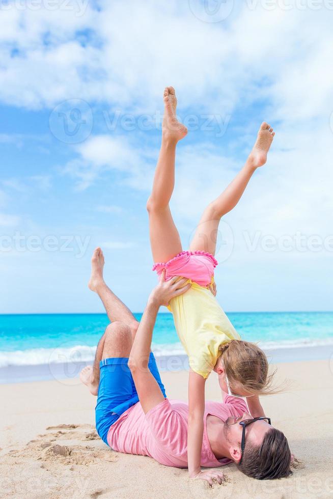 familie des vaters und des sportlichen kleinen mädchens, die spaß am strand haben foto