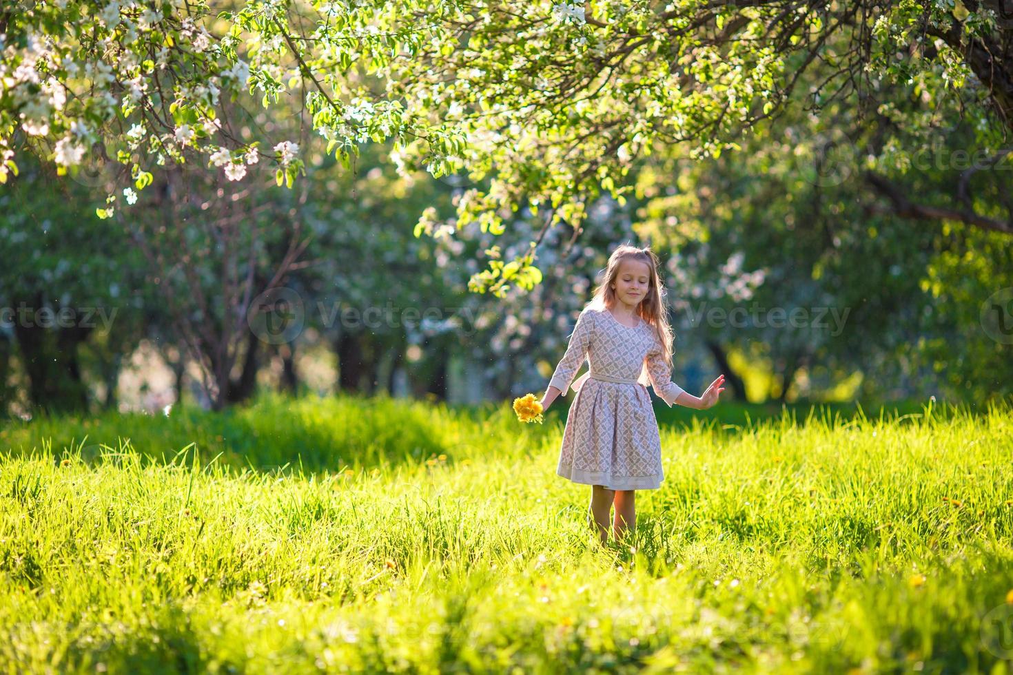 kleines Mädchen im blühenden Apfelgarten im Freien foto