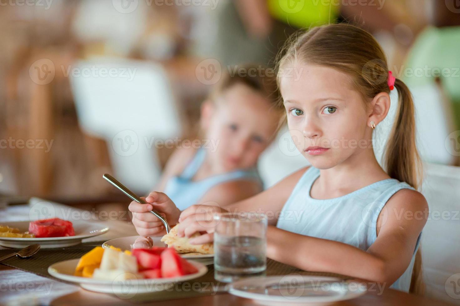 entzückende kleine Mädchen, die im Restaurant des Resorts frühstücken foto