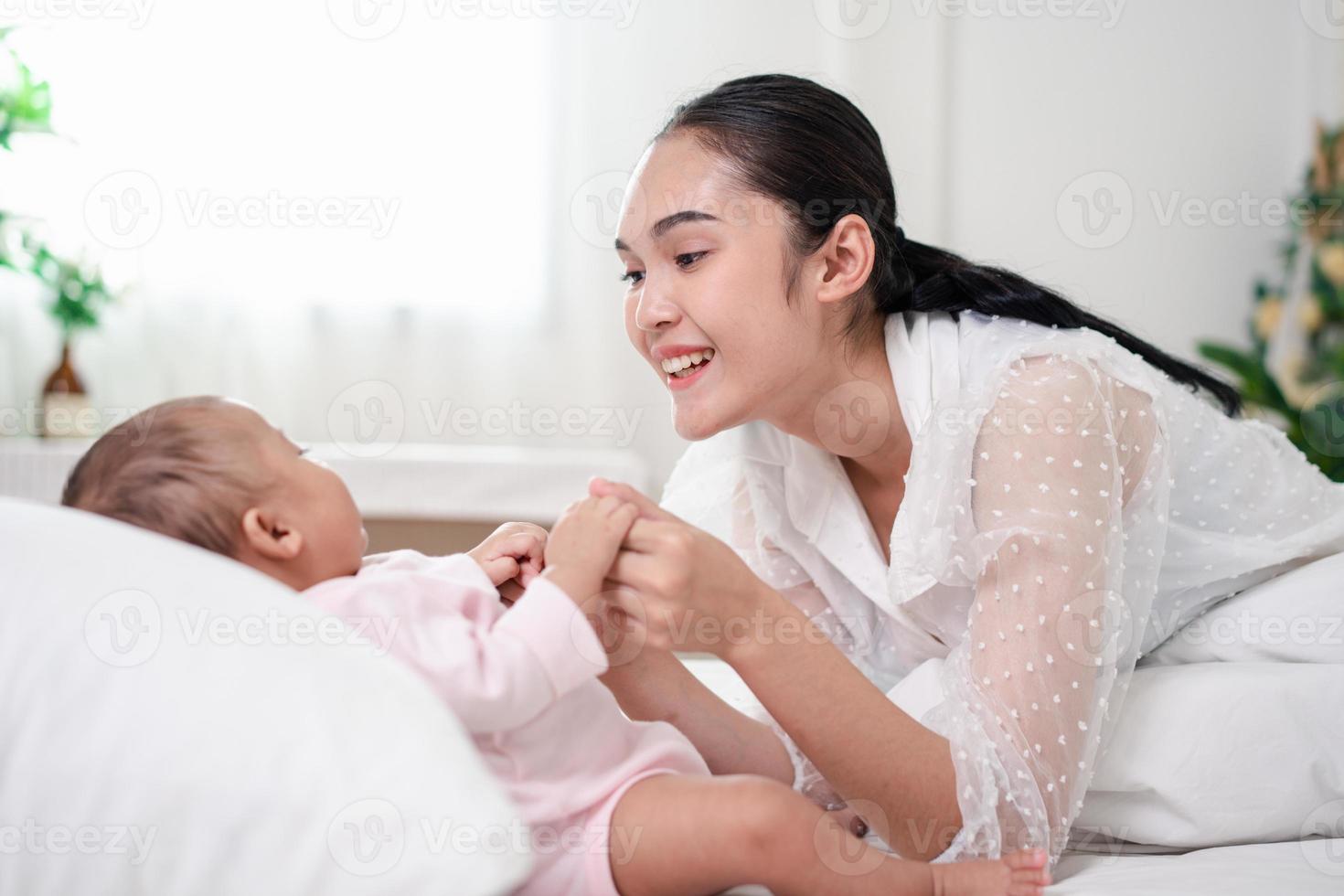 Muttererziehung und neugeborenes Geburtsleben. mutter und baby spielen im sonnigen schlafzimmer, familie hat spaß zusammen. kinderbetreuung, mutterschaftskonzept. foto