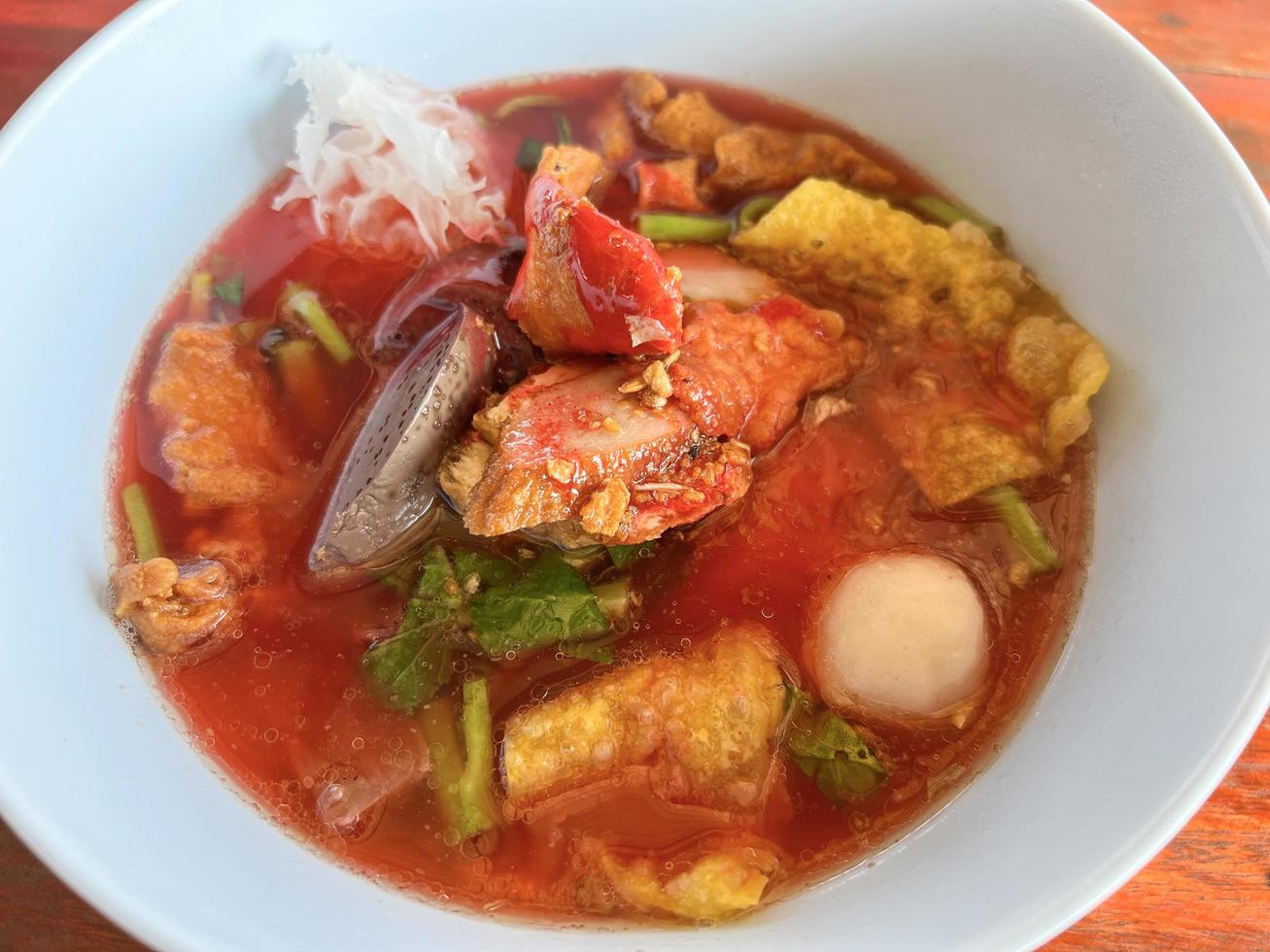 essen thailändische nudeln mit sortiertem tofu und fischbällchen in roter suppe - asiatische flache nudeln mit rosa meeresfrüchten auf suppenschüssel foto