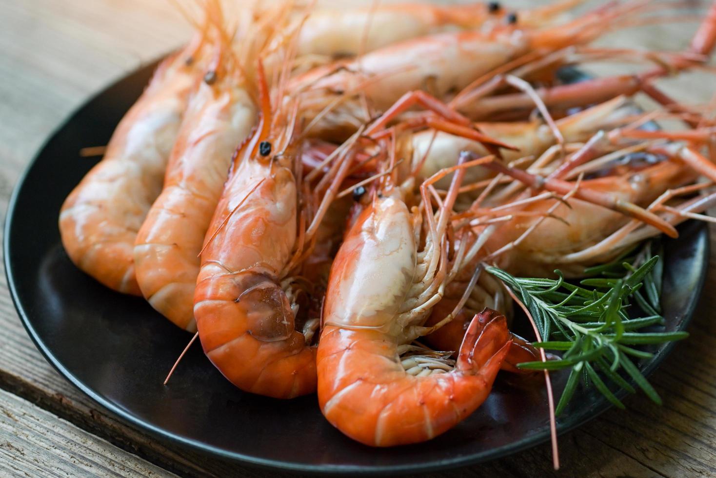 Garnelen gegrillte köstliche Gewürzgewürze auf Plattenhintergrund, appetitlich gekochte Garnelen, gebackene Garnelen, Rosmarin, Zitrone, Limettenpfeffer, Meeresfrüchte mit Shelfish foto