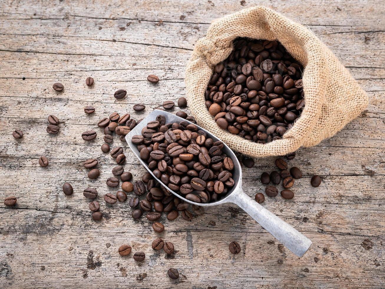 Hintergrund dunkel gerösteter Kaffeebohnen mit Schaufeln auf Holzhintergrund mit Kopierraum. foto