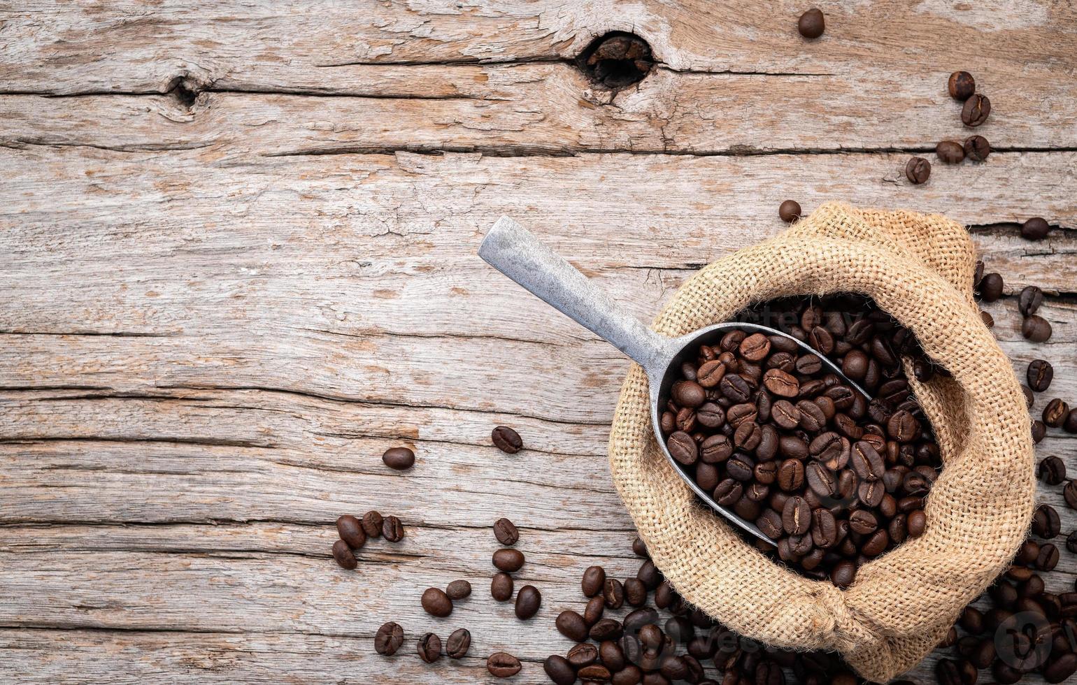 Hintergrund dunkel gerösteter Kaffeebohnen mit Schaufeln auf Holzhintergrund mit Kopierraum. foto