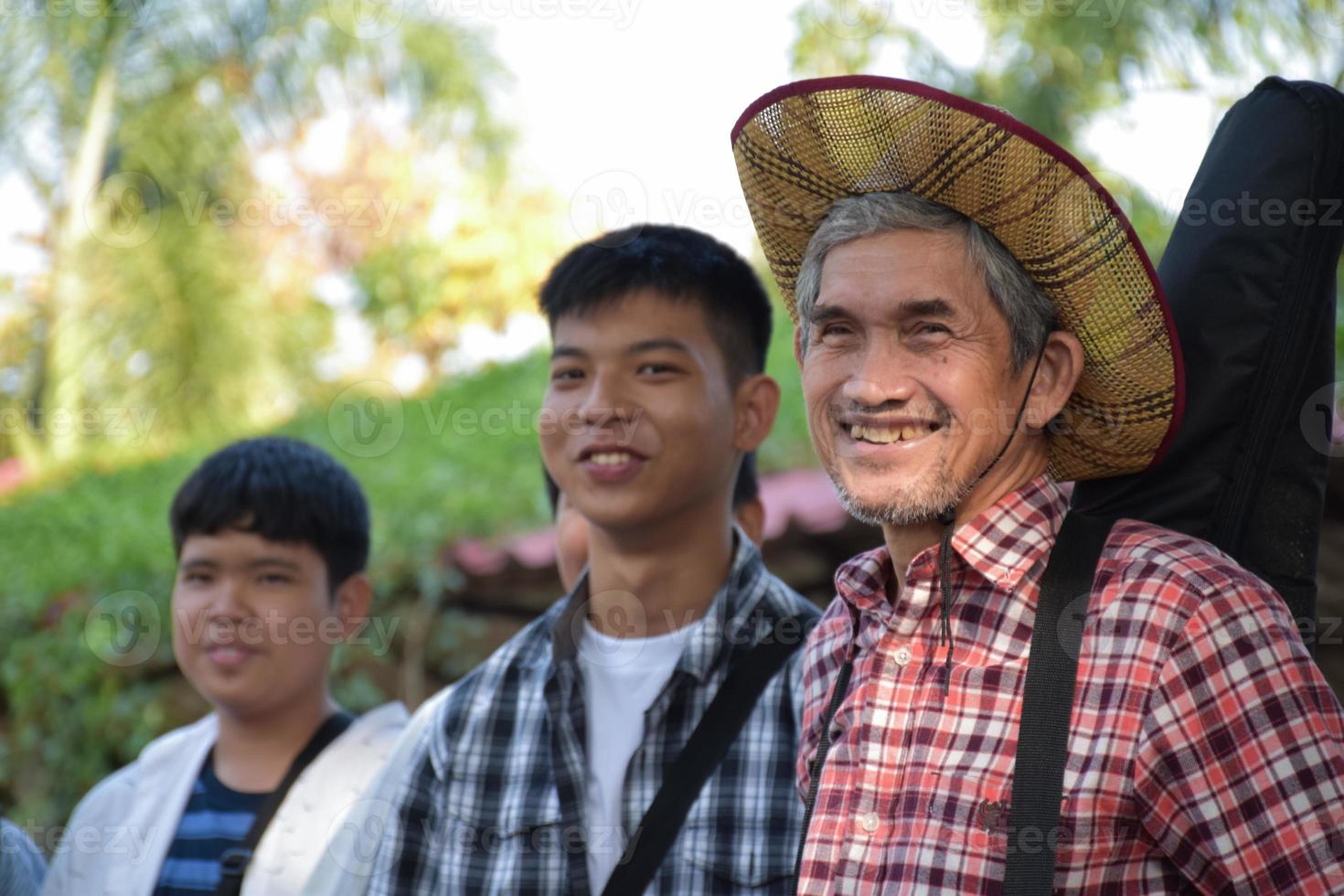 porträt älterer asiatischer musiklehrer, der zusammen mit seinen schülern während des musikunterrichts im freien steht, weicher und selektiver fokus, erwachsener hilft schülern beim konzept der schulprojektarbeit. foto