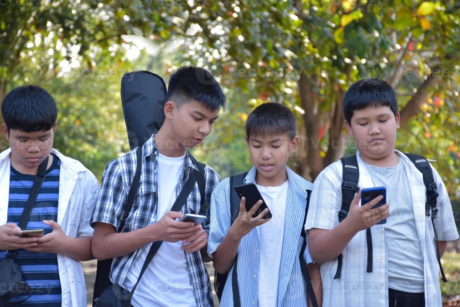 weicher fokus junge asiatische teenager zeigen ihren freunden ihre eigenen handys, während sie nach hause gehen, nachdem sie musikunterricht genommen und gemeinsam schulprojektarbeit in der schule gemacht haben. foto