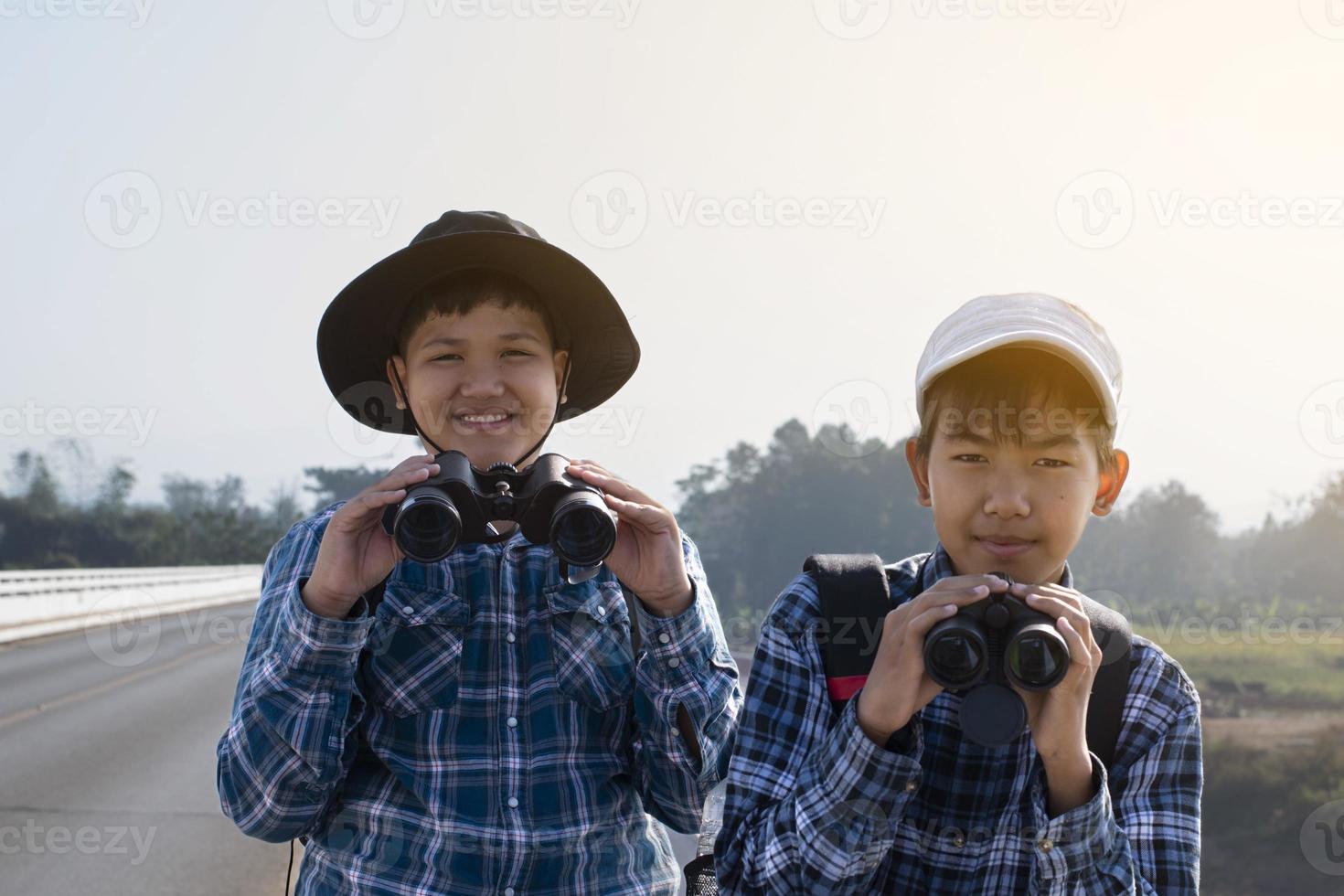 asiatische Jungs benutzen Ferngläser, um während des Sommercamps Vögel im tropischen Wald zu beobachten, eine Idee, um Kreaturen und wild lebende Tiere und Insekten außerhalb des Klassenzimmers zu lernen. foto