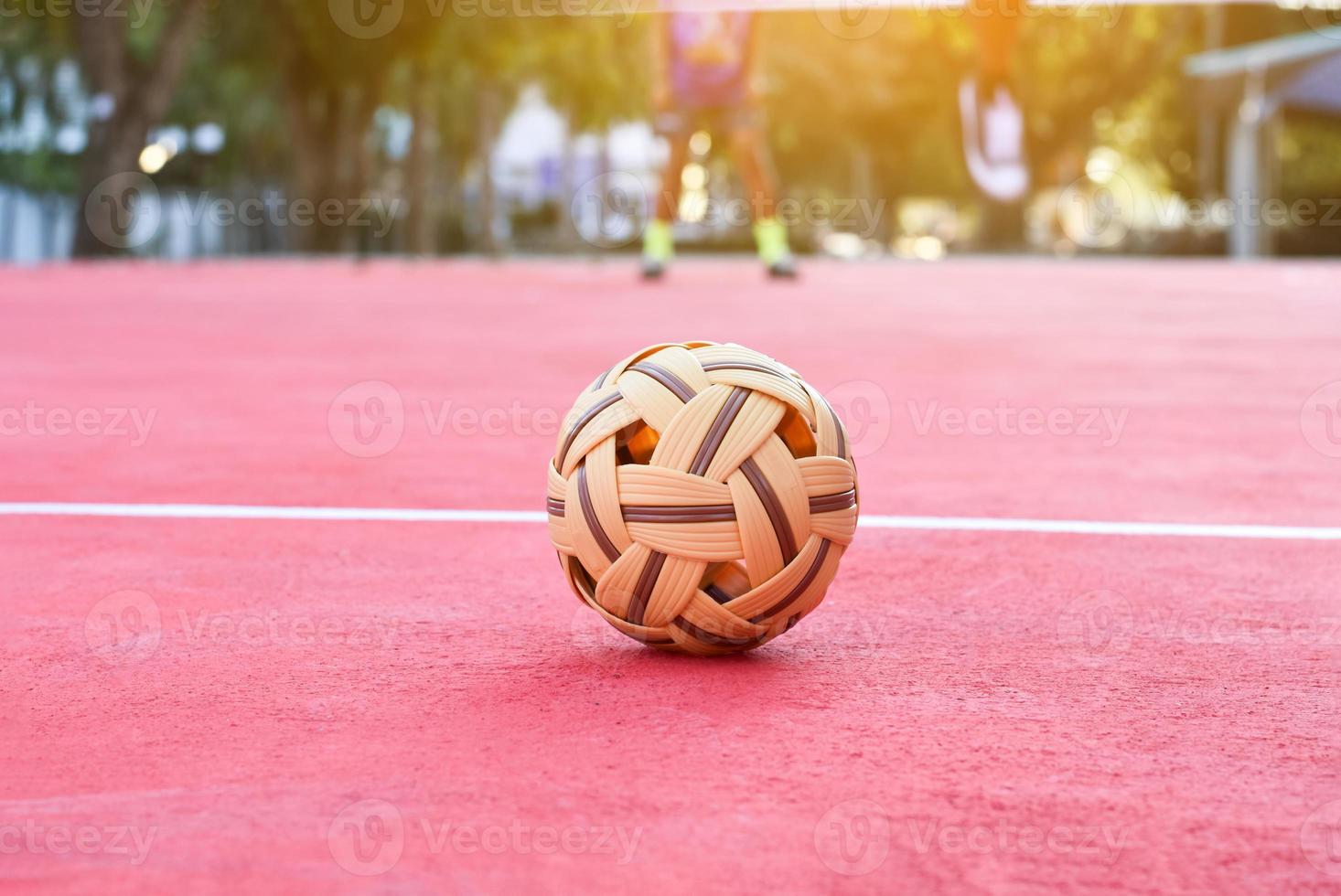 sepak takraw ball auf rotem boden des außenplatzes, unscharfer hintergrund, freizeitaktivitäten und outdoor-sportarten in südostasiatischen ländern konzept. foto