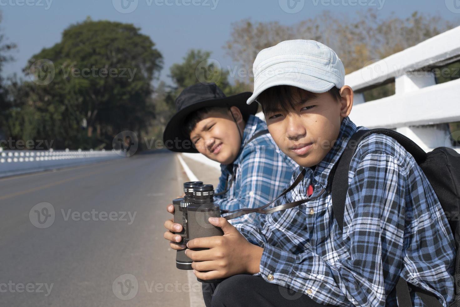 asiatische Jungs benutzen Ferngläser, um während des Sommercamps Vögel im tropischen Wald zu beobachten, eine Idee, um Kreaturen und wild lebende Tiere und Insekten außerhalb des Klassenzimmers zu lernen. foto
