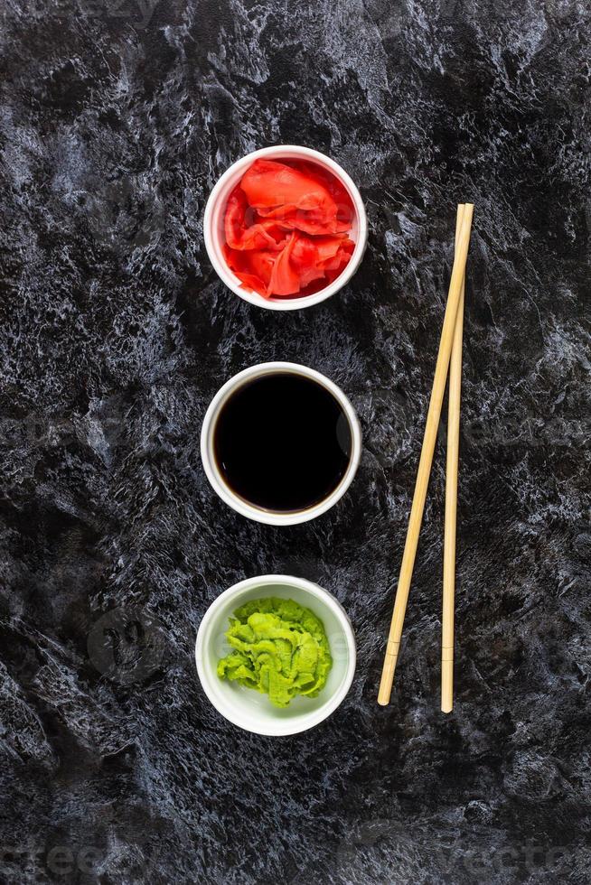 Set für Sushi-Sojasauce Ingwer-Wasabi mit Stäbchen auf Steinhintergrund foto