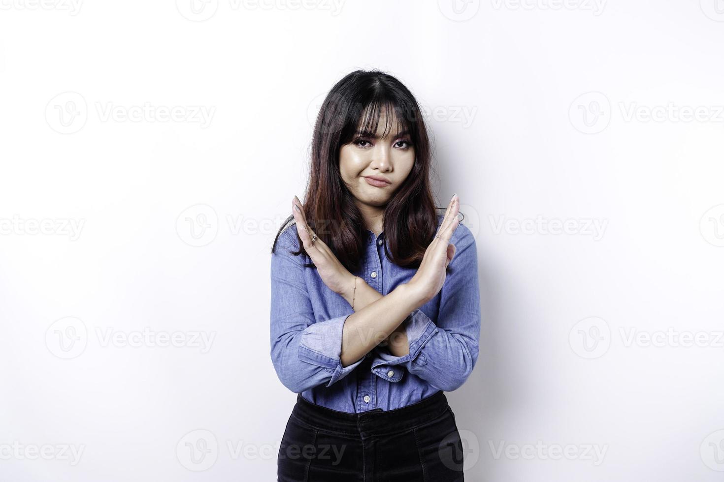 schöne asiatische frau, die blaues hemd mit handgeste trägt, stellt ablehnung oder verbot mit kopienraum dar foto