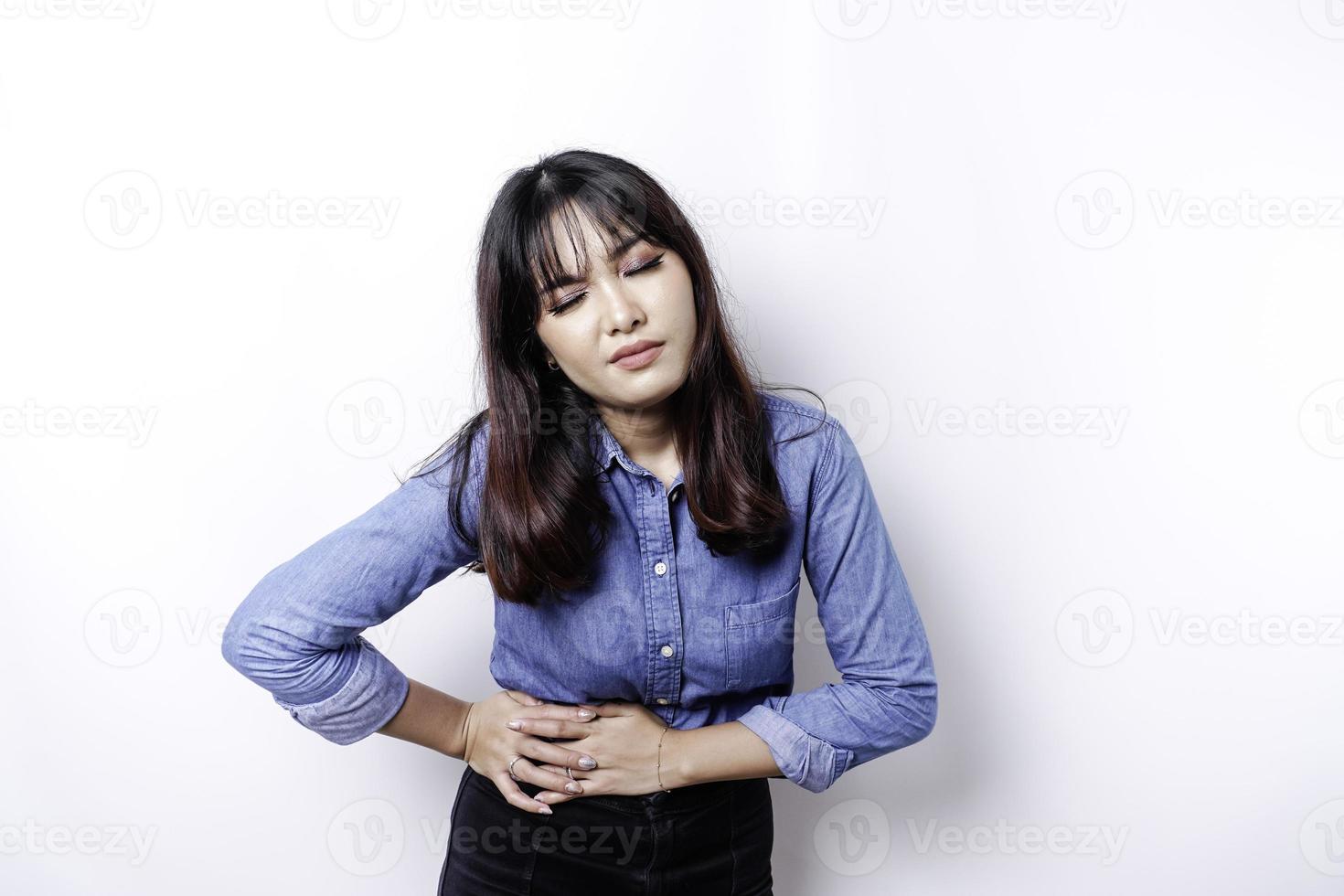 Foto einer jungen unwohl kranken kranken Frau, die die Hand auf dem Bauch hält, leidet Schmerzen isoliert auf weißem Hintergrund