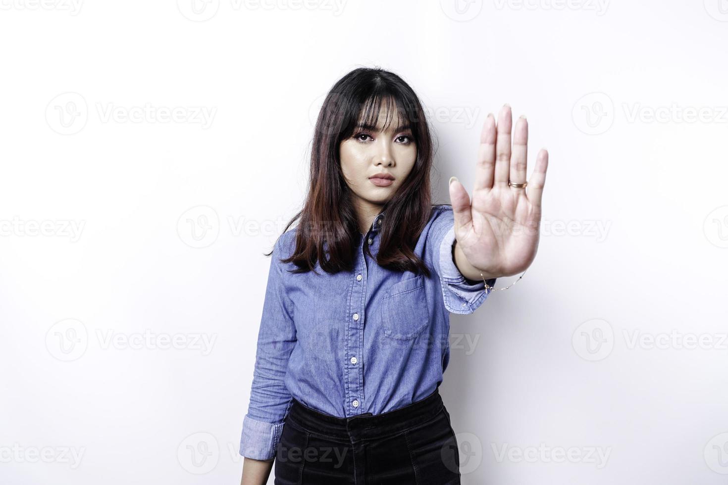schöne asiatische frau, die blaues hemd mit handgestenhaltung des stopps oder des verbots mit kopienraum trägt foto