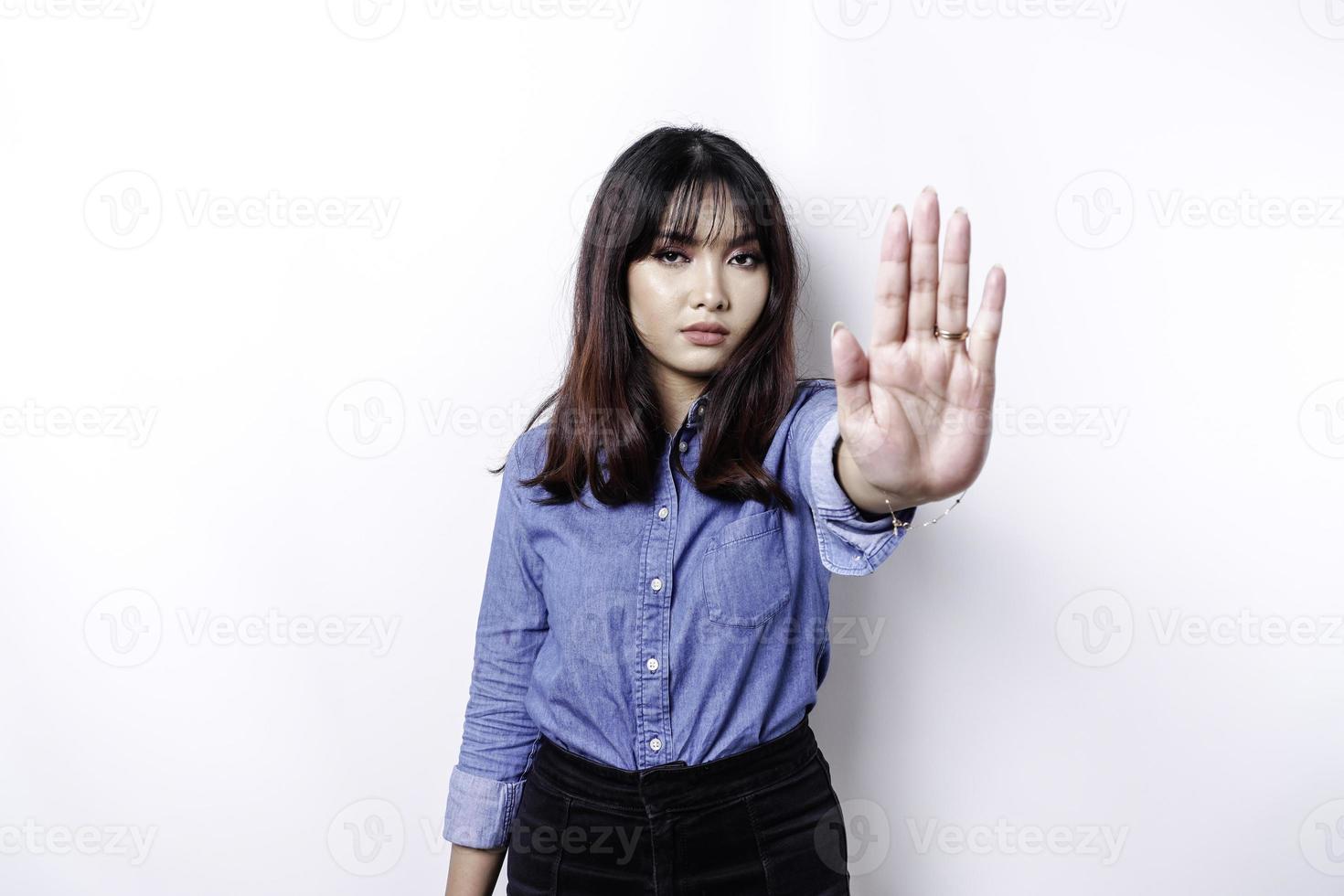 schöne asiatische frau, die blaues hemd mit handgestenhaltung des stopps oder des verbots mit kopienraum trägt foto