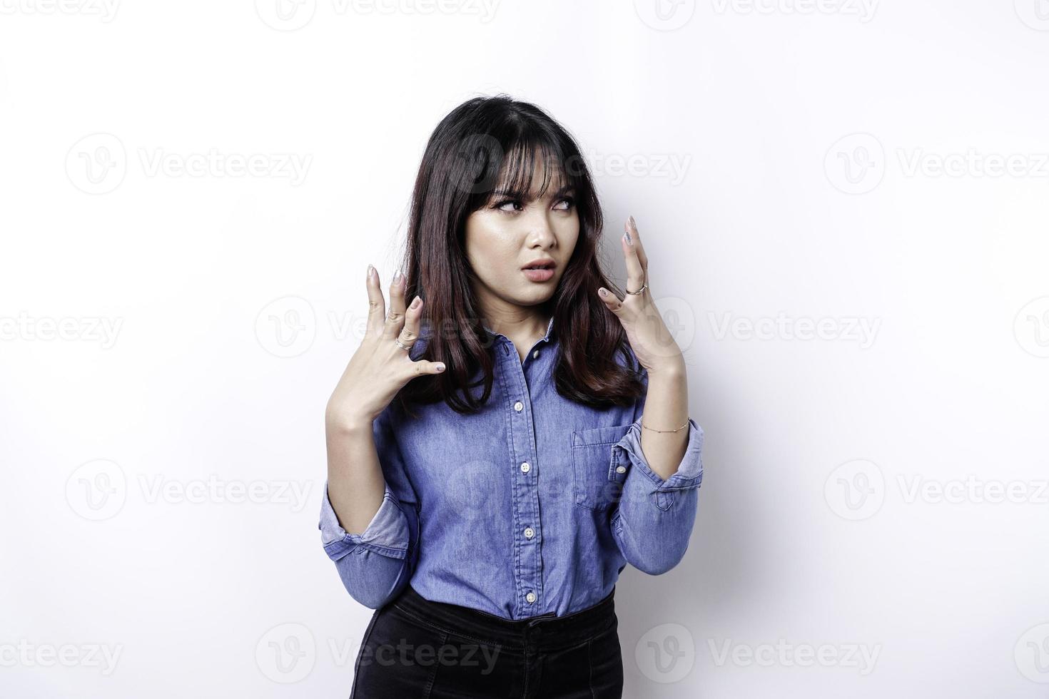 ein porträt einer asiatischen frau, die ein blaues hemd trägt, das durch weißen hintergrund isoliert ist, sieht deprimiert aus foto