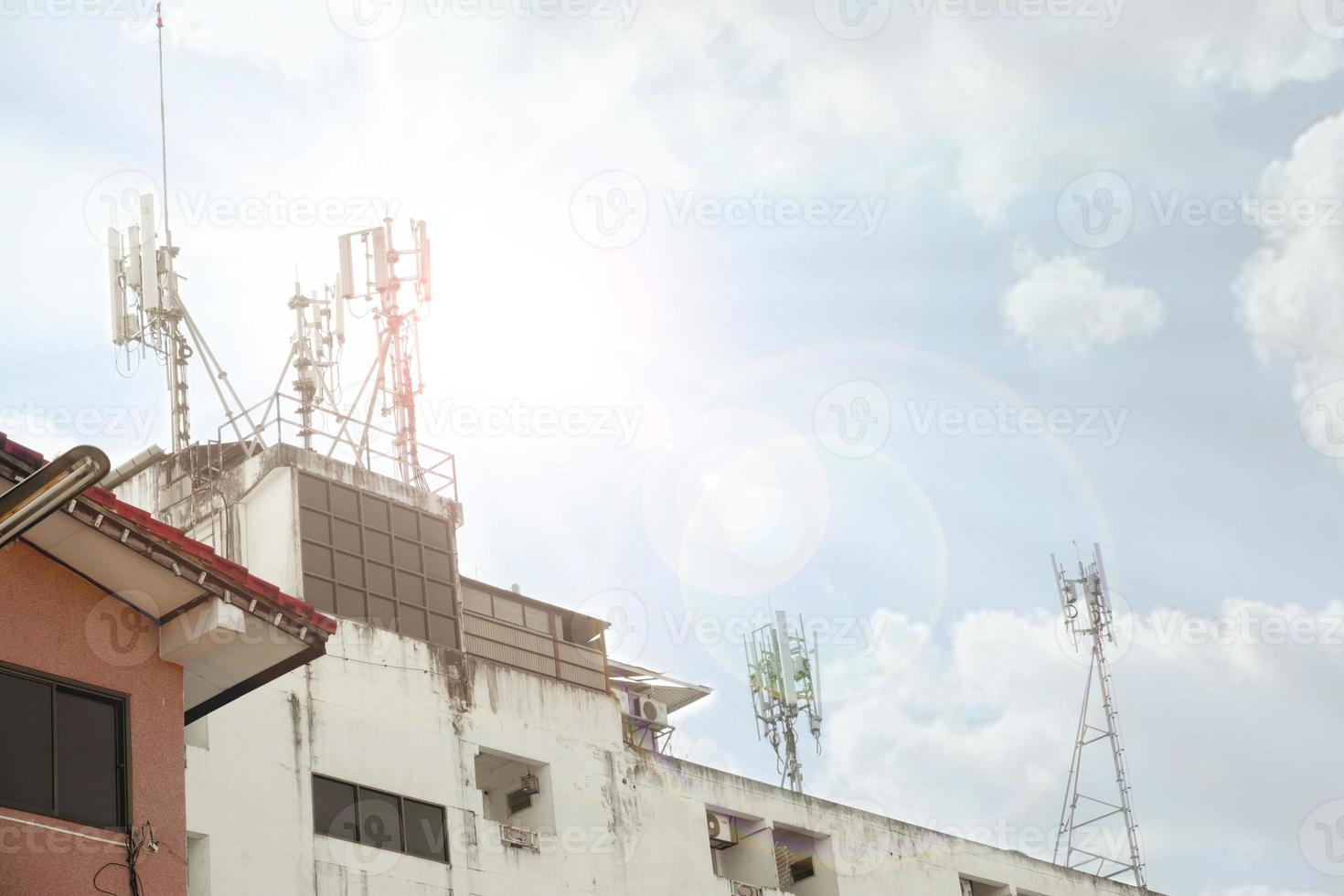 Kommunikationsturm mit Antennen in verschiedenen Größen auf der Spitze des Gebäudes am strahlend blauen Himmel mit Wolkenhintergrund. foto
