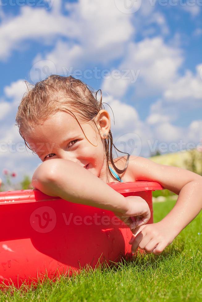 Porträt eines lächelnden, charmanten kleinen Mädchens, das ihren Urlaub im Pool im Freien genießt foto